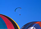 Balloons form foreground for powered paraglider.